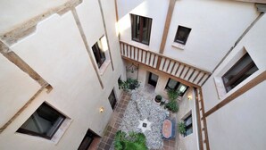 A courtyard with a tiled floor, potted plants, and a star-shaped mosaic. - Céntrico impresionante ático con vistas del cathedral  (Toledo)