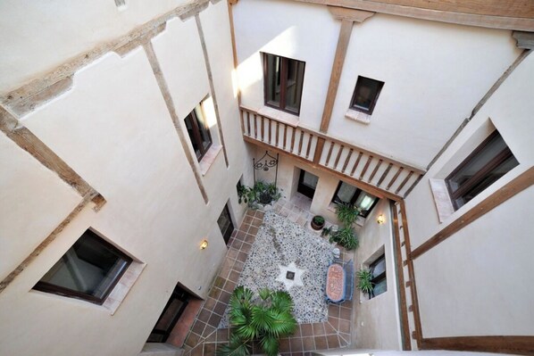 A courtyard with a tiled floor, potted plants, and a star-shaped mosaic. - Céntrico impresionante ático con vistas del cathedral  (Toledo)