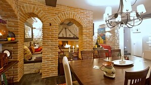 A cozy dining area with a stone fireplace, wooden furniture, and a chandelier. - Sea view, garden with barbecue, pool with loungers, parking, air conditioning, wifi (Rojci)