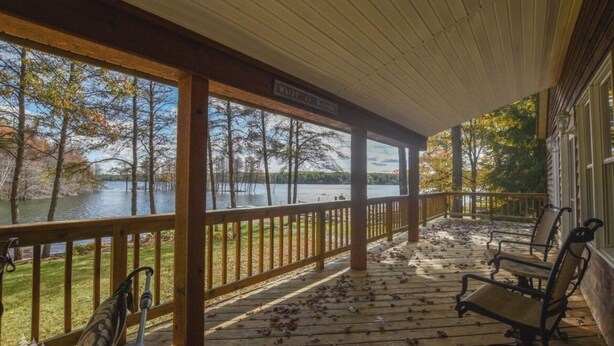 Eine überdachte Veranda mit Blick auf einen See, Holzbanken und einem Schild mit der Aufschrift 'Whistling Swamp'.