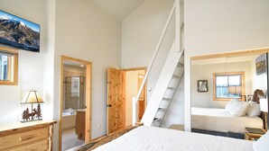 A bedroom with a bed, a wooden dresser, a mirror, and a window.