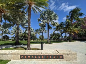 A sign for 'Pompano Beach' with palm trees and a clear sky in the background. - Ocean Breeze Villa 🏝️ 5 Minute Walk to Beach (Pompano Beach)