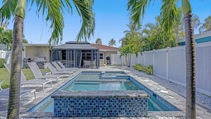 A swimming pool with lounge chairs and a patio area, surrounded by palm trees and a white fence. - Ocean Breeze Villa 🏝️ 5 Minute Walk to Beach (Pompano Beach)