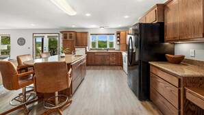 Eine moderne Küche mit Holzausstattung, einem schwarzen Kühlschrank und einem Essbereich mit Tisch und Stühlen.