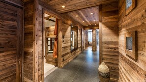 Un couloir en bois, avec un sol carrelé, des murs en bois et un grand miroir.