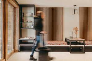 A modern living room with a glass display unit, a cushioned bench, and a small table with a vase. - Vail Lodge by Alpine Resorts (Val-d'Isere)