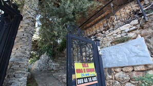 Un muro de piedra con una reja de metal y un letrero que indica servicio las 24 horas.