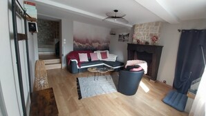 A living room with a sofa, a coffee table, a fireplace, and a staircase leading to another room. - "Les 4 Fils Aymon" House overlooking the Meuse. (Bogny-sur-Meuse)