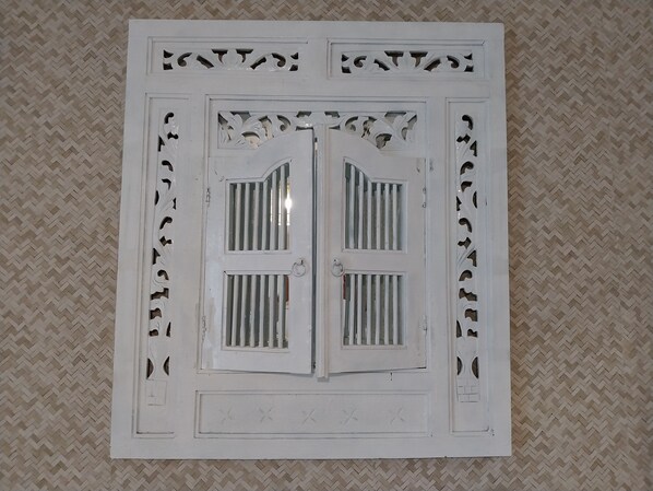 A white decorative panel with intricate cut-out designs and a central door with barred windows.