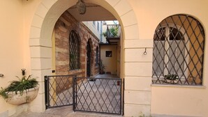 An arched entrance with a metal gate, a potted plant, and a window with a metal grille. - Aristocratic Residence  (Verona)
