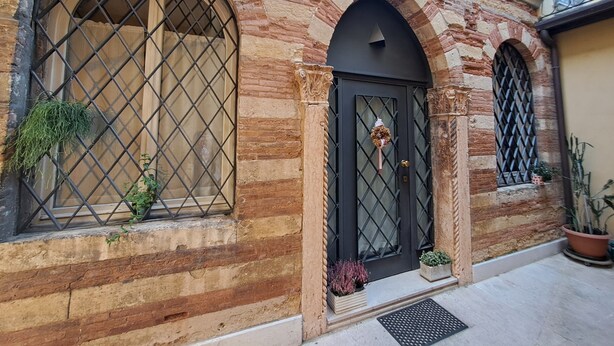 A building with arched windows, a black door, and potted plants. - Aristocratic Residence  (Verona)