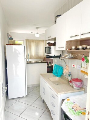 Uma cozinha compacta com geladeira, micro-ondas, pia e armários.