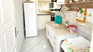 Een kleine keuken met een koelkast, een spoelbak en een magnetron.