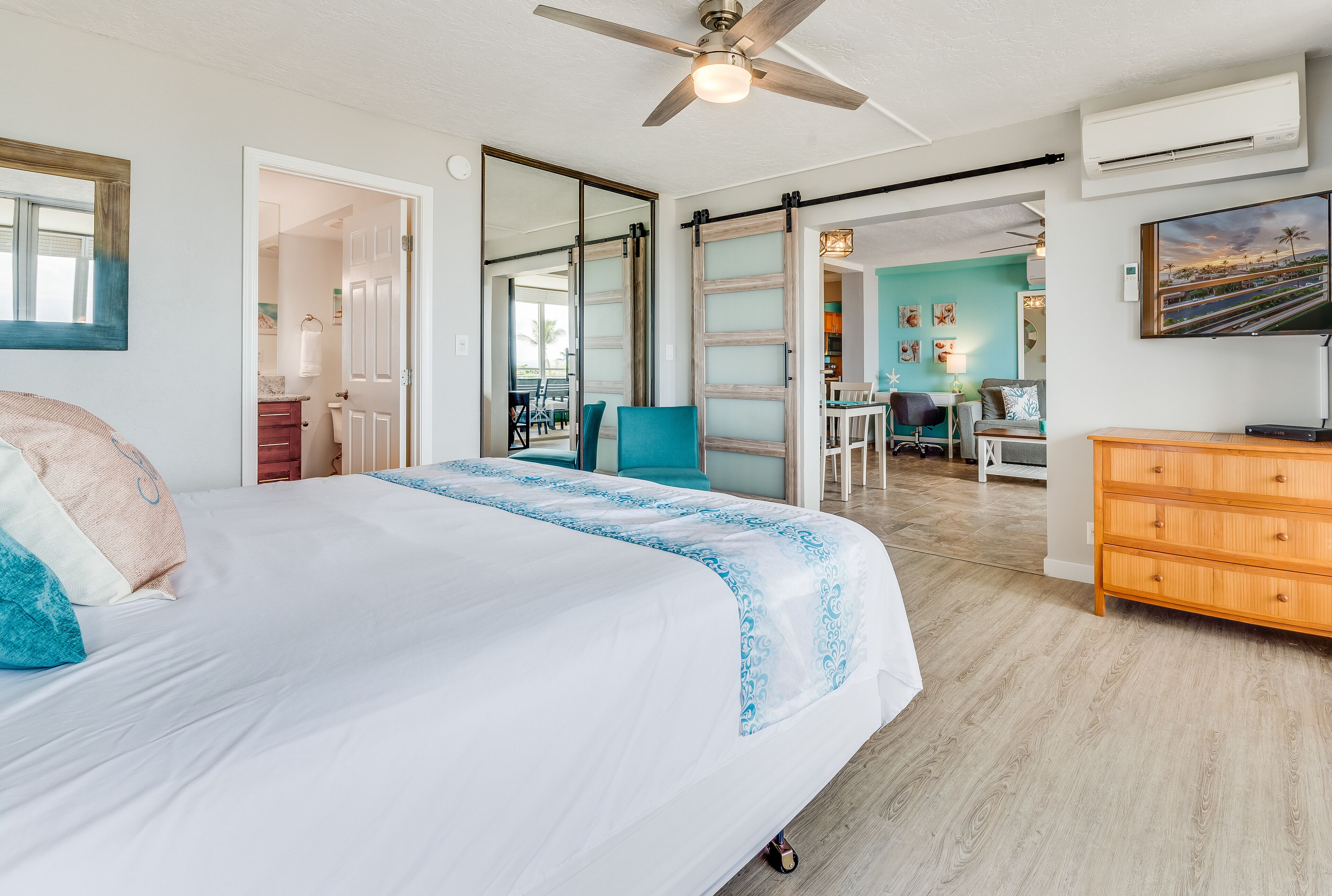A bedroom with a bed, a ceiling fan, a wooden dresser, and a TV.