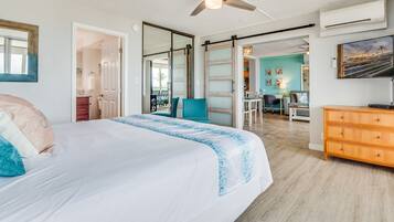 A bedroom with a bed, a ceiling fan, a wooden dresser, and a TV.