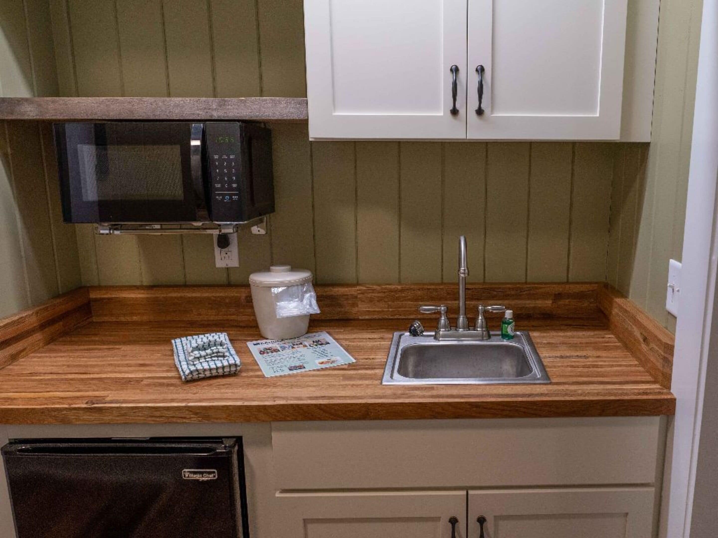 Cocina compacta con microondas, pileta y heladera pequeña.
