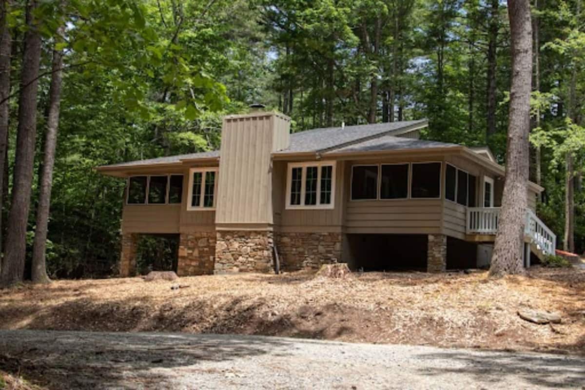 A two-story house with a stone foundation, large windows, and a covered porch.