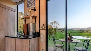A modern kitchen with wooden cabinets, a black countertop, and a view of a scenic landscape through large windows.