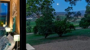 A room with a large window overlooking a grassy landscape and a tree.