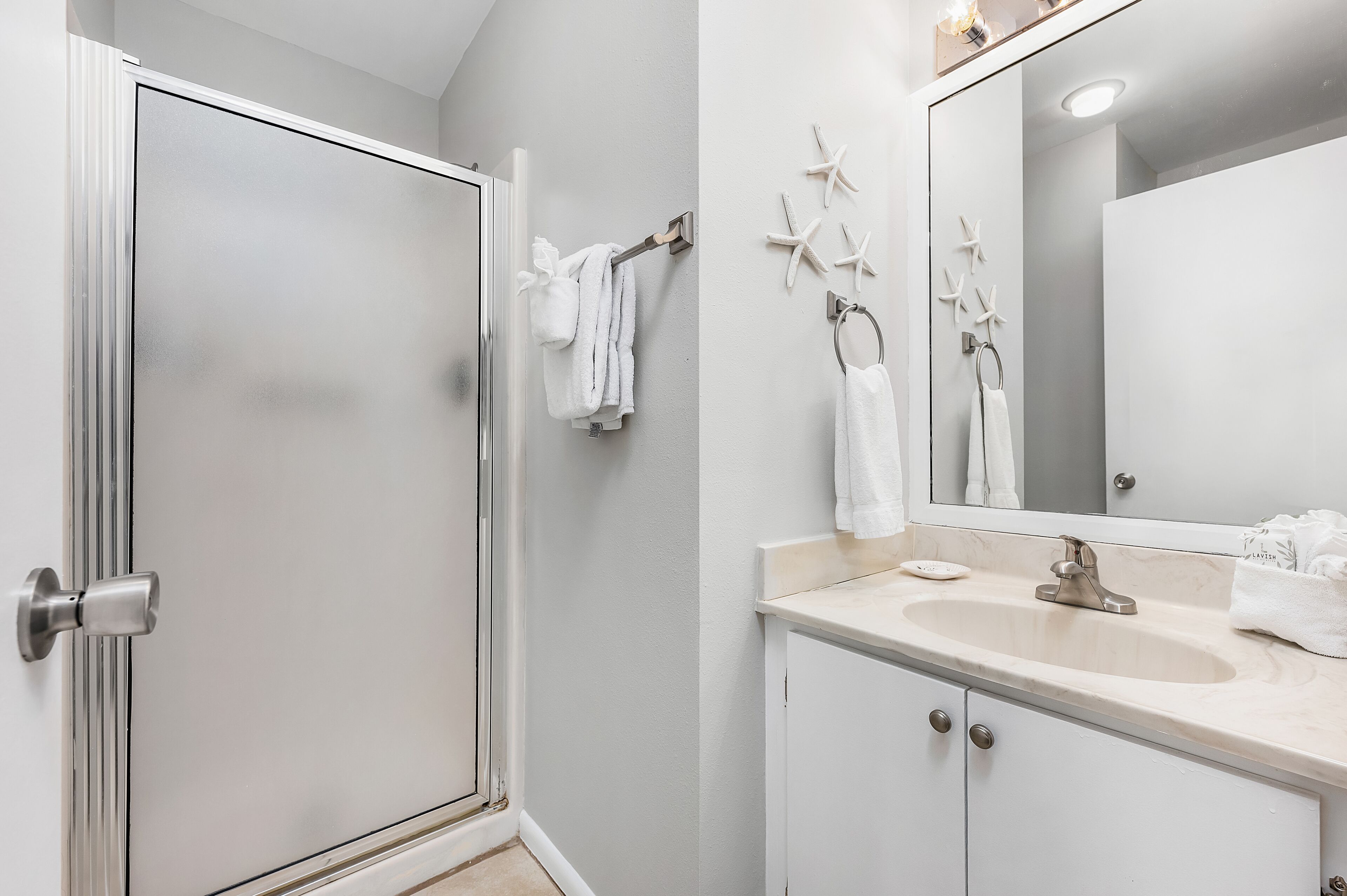 Un baño con ducha, lavamanos y espejo.
