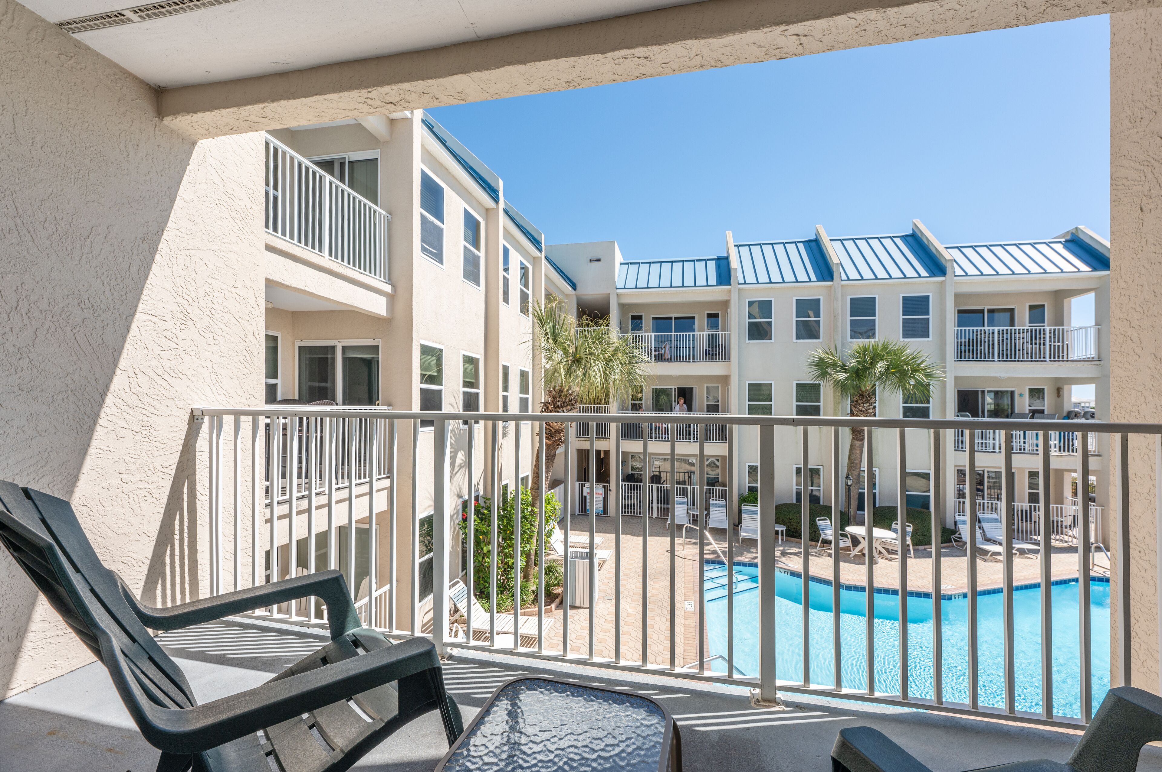 Un balcon donnant sur une piscine et les bâtiments adjacents.
