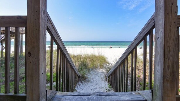 Un escalier en bois mène à une plage d’où l’on a une vue dégagée sur l’océan.