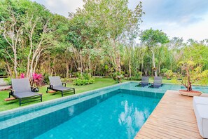 Una piscina techada, sombrillas, sillones reclinables de piscina