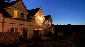 Una casa a due piani con un balcone, un patio e un piccolo giardino.