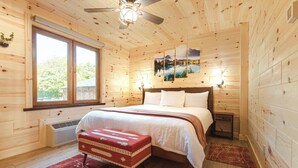 Camera da letto in una baita di legno, con un letto, una finestra, un termosifone e un'opera d'arte appesa al muro.