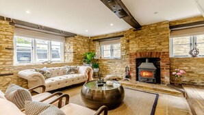 Una sala de estar acogedora con pared de piedra, chimenea, sofá y una mesa de centro.