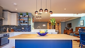Una cocina moderna con una isla central, electrodomésticos integrados e iluminación colgante.