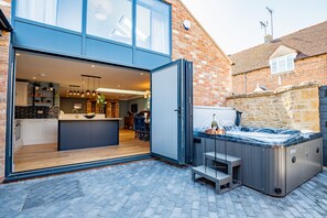 A modern kitchen with a large island, a hot tub, and a stone wall. - The Old Candle Shop - sleeps 4 guests  in 2 bedrooms (Moreton-in-Marsh)