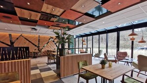 A modern interior with a checkered floor, wooden reception desk, and seating areas. - Appartementen De Egmonden (Egmond aan Zee)