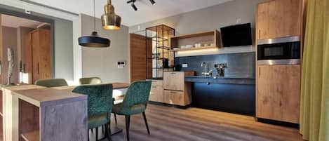 A modern kitchen with wooden cabinets, a built-in oven, and a dining area with a wooden table and chairs.