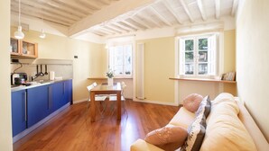 Eine geräumige Küche mit blauen Schränken, einem Holztisch und einem beigen Sofa mit Kissen.