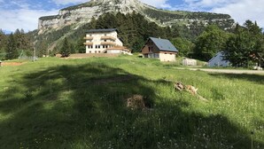 A building with a flat roof and a balcony, surrounded by a grassy area and trees. - 4-6 Pers apartment in the heart of the Chartreuse at the foot of the ski slopes (Sarcenas)