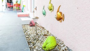 Ein schmaler Außenkorridor mit bunten Stühlen und einer Wandleuchte.