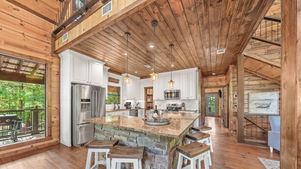 A spacious kitchen with a large island, white cabinetry, and a view of the outdoors.