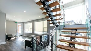 A modern interior with a glass staircase, large windows, and a flat floor plan. - 107 Birchview Trail (The Blue Mountains)