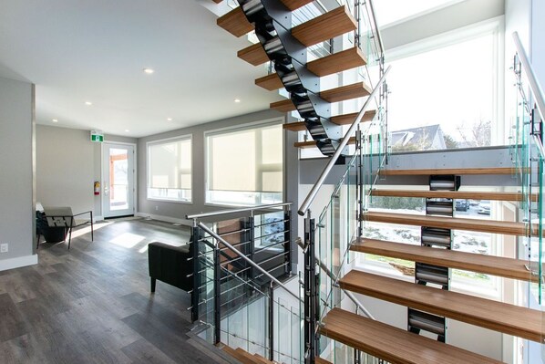 Un interior moderno con una escalera de cristal, amplias ventanas y un diseño de planta abierta.