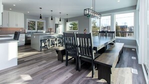 A modern kitchen with white cabinets, a central island, and a dining area with dark chairs and benches. - 107 Birchview Trail (The Blue Mountains)