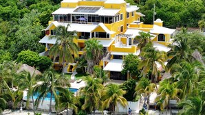 Un edificio amarillo de varios pisos con piscina y palmeras.