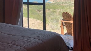 A room with a large window, a bed, and a wooden chair. - Denmoza Eco Lodge Glamping (Potrerillos)
