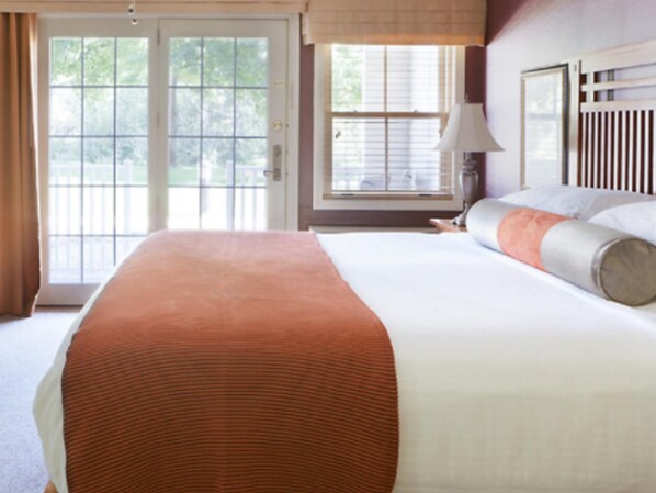 Habitación de hotel con una cama grande, una ventana con persianas, una lámpara y vistas a zonas verdes.