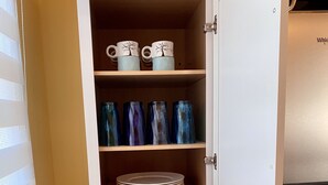 A kitchen pantry with shelves holding plates, bowls, and glassware. - Ellie’s Loft in the heart of downtown Nashville, IN. (Nashville)