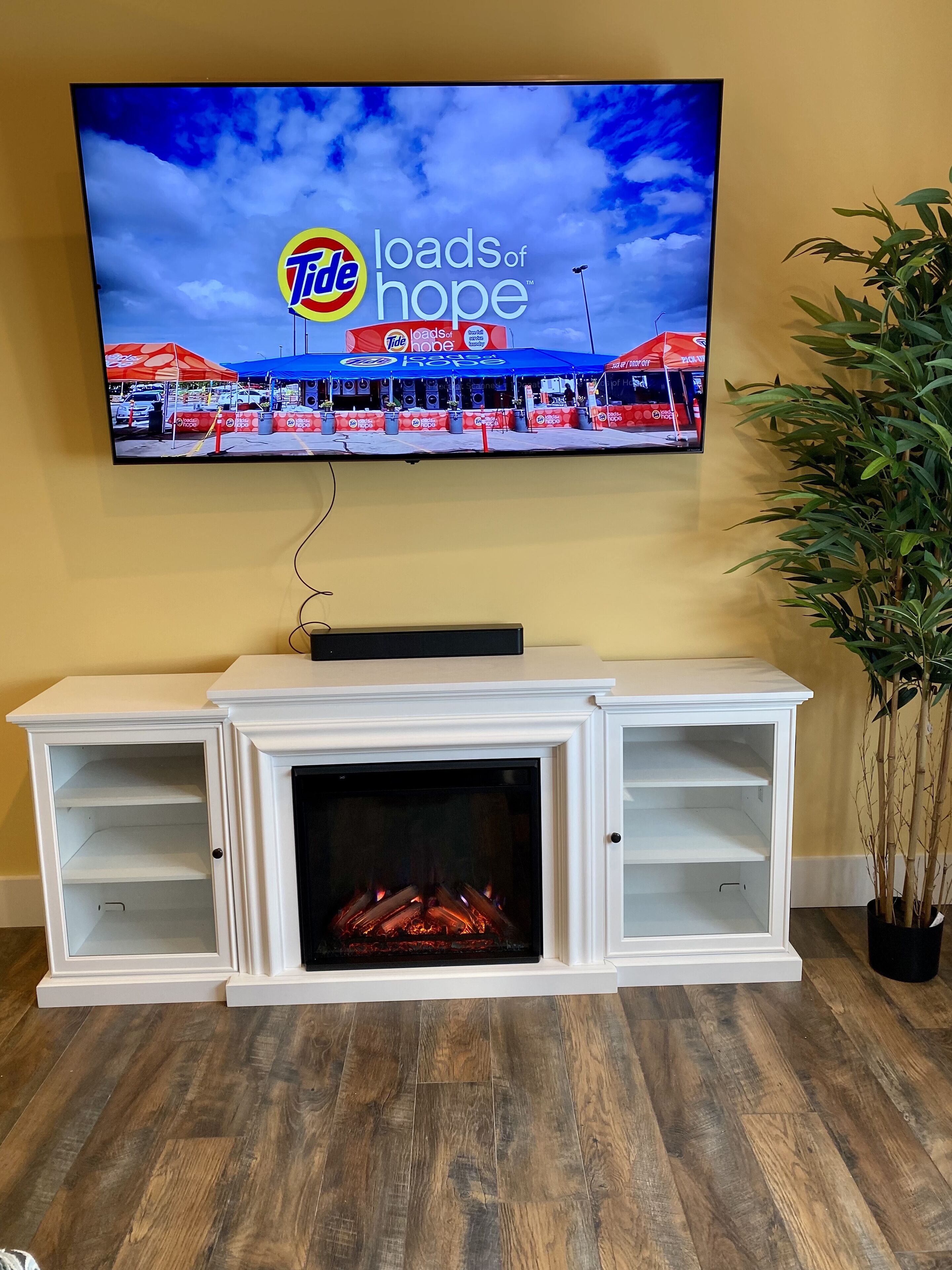 A television mounted on a wall displaying a Tide advertisement.