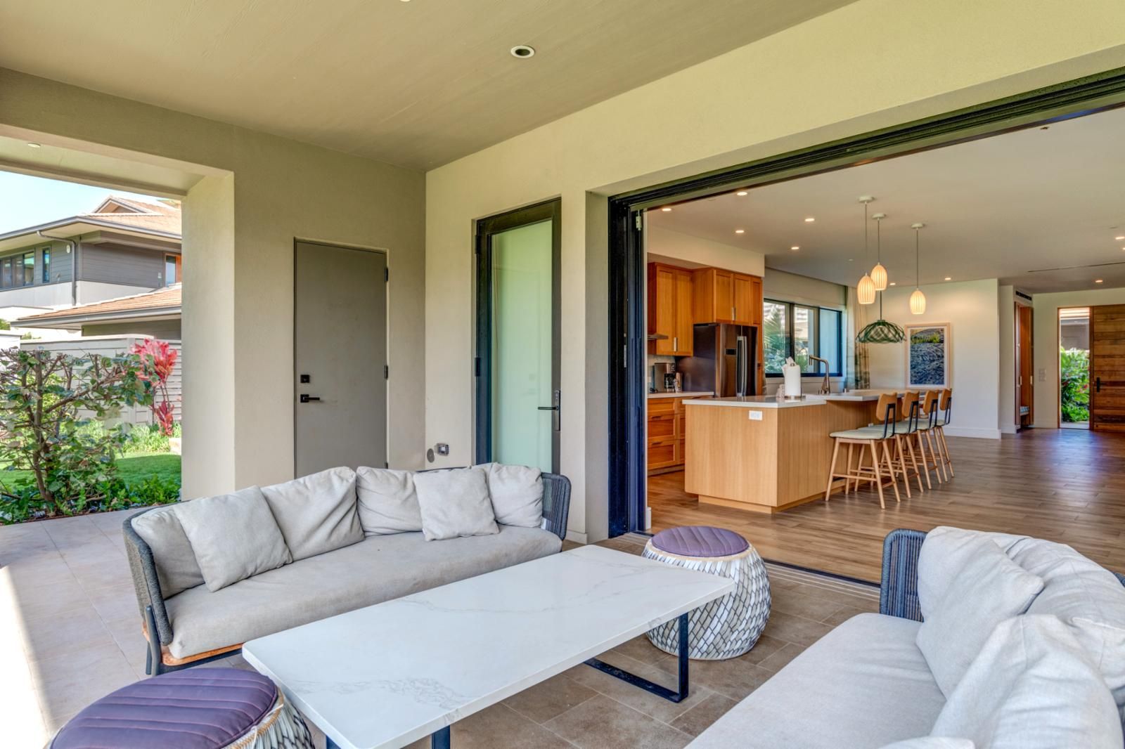 A modern living room with a sofa, a dining table, and a kitchen area visible through an open door.
