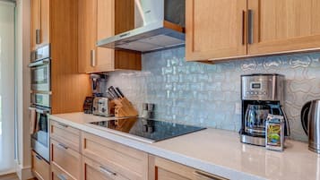A modern kitchen with wooden cabinets, stainless steel appliances, a coffee maker, and a toaster.