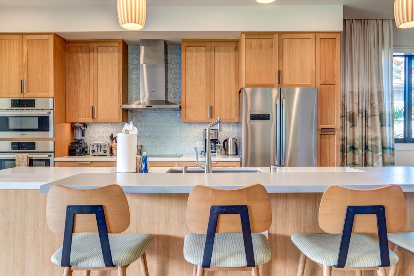 A modern kitchen with wooden cabinets, stainless steel appliances, and a central island with bar stools.