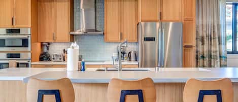 A modern kitchen with wooden cabinets, stainless steel appliances, and a central island with bar stools.